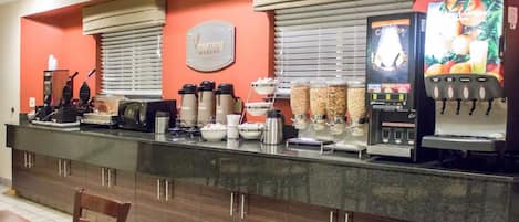 A breakfast bar with coffee machines, a juice dispenser, and a sign that reads "morning buffet."