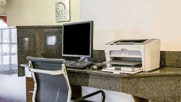 Un comptoir d’accueil équipé d’un ordinateur, d’une imprimante et d’une chaise.