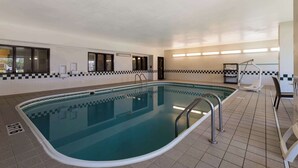 An indoor swimming pool with clear water, tiled floor, and a checkered wall pattern.