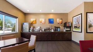 A hotel kitchen with a buffet setup, including a refrigerator, coffee maker, and various food items.