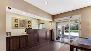 A reception area with a wooden counter, a large window, and a sliding glass door leading outside. - Comfort Inn Wichita East (Wichita)