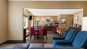 A hotel lobby with a seating area, a dining table, and a kitchen in the background. - Comfort Inn Wichita East (Wichita)