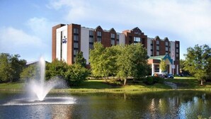 A hotel with a large building, a fountain, and a pond.
