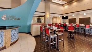 A hotel lobby with a reception desk, seating area, and a dining section.