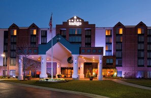 A hotel with a prominent 'indigo' sign, a flag, and a well-lit entrance. - Hotel Indigo Chicago-Vernon Hills by IHG (Vernon Hills)