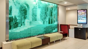 A reception area with a large digital display, a seating area with a bench, and a reception desk.