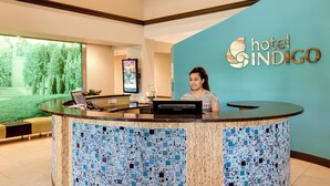 A hotel reception desk with a digital screen, a water dispenser, and a sign for 'hotel INDIGO'.