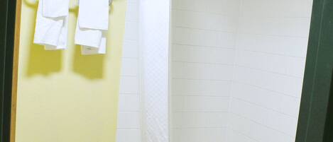 A bathroom with a shower, a towel rack with towels, and a toilet.