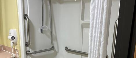 Una bañera con cabezal de ducha, barras de apoyo y ducha de mano.