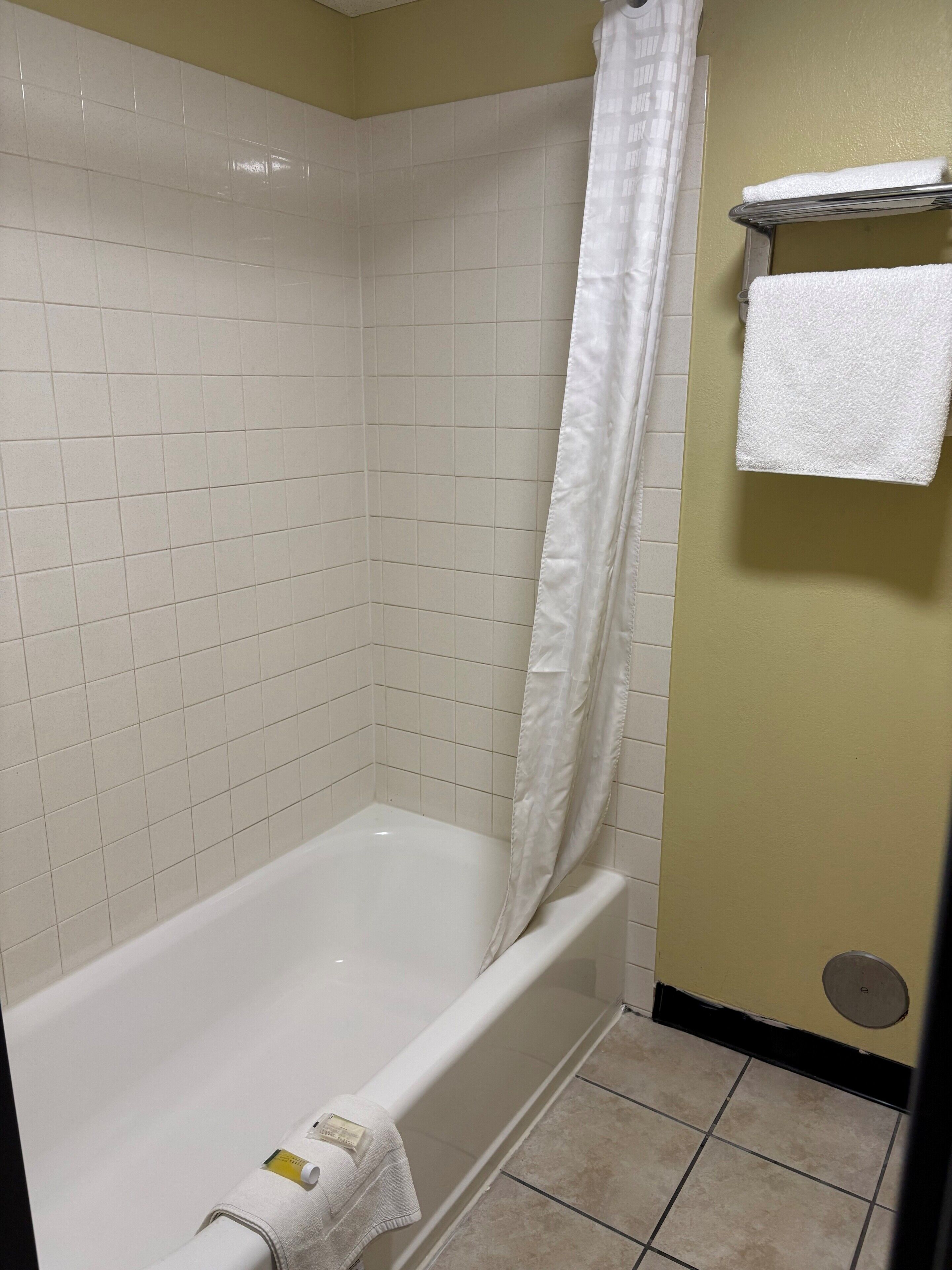 Une salle de bain avec une baignoire blanche, un rideau de douche et un porte-serviettes avec une serviette.