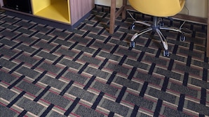 Une chambre d’hôtel équipée d’un bureau, d’une chaise, d’une télévision et d’un petit réfrigérateur.