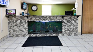 Une salle d’attente avec un aquarium, une horloge et un téléviseur fixé au mur.