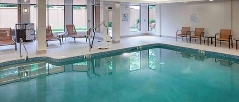 Una piscina interior con sillas de descanso y un elevador de piscina.