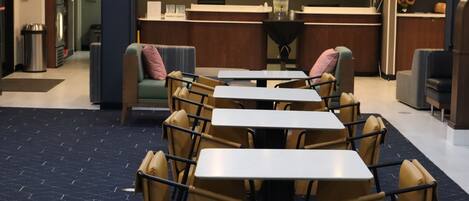 A restaurant with tables and chairs, a counter, and a wall with a decorative item.