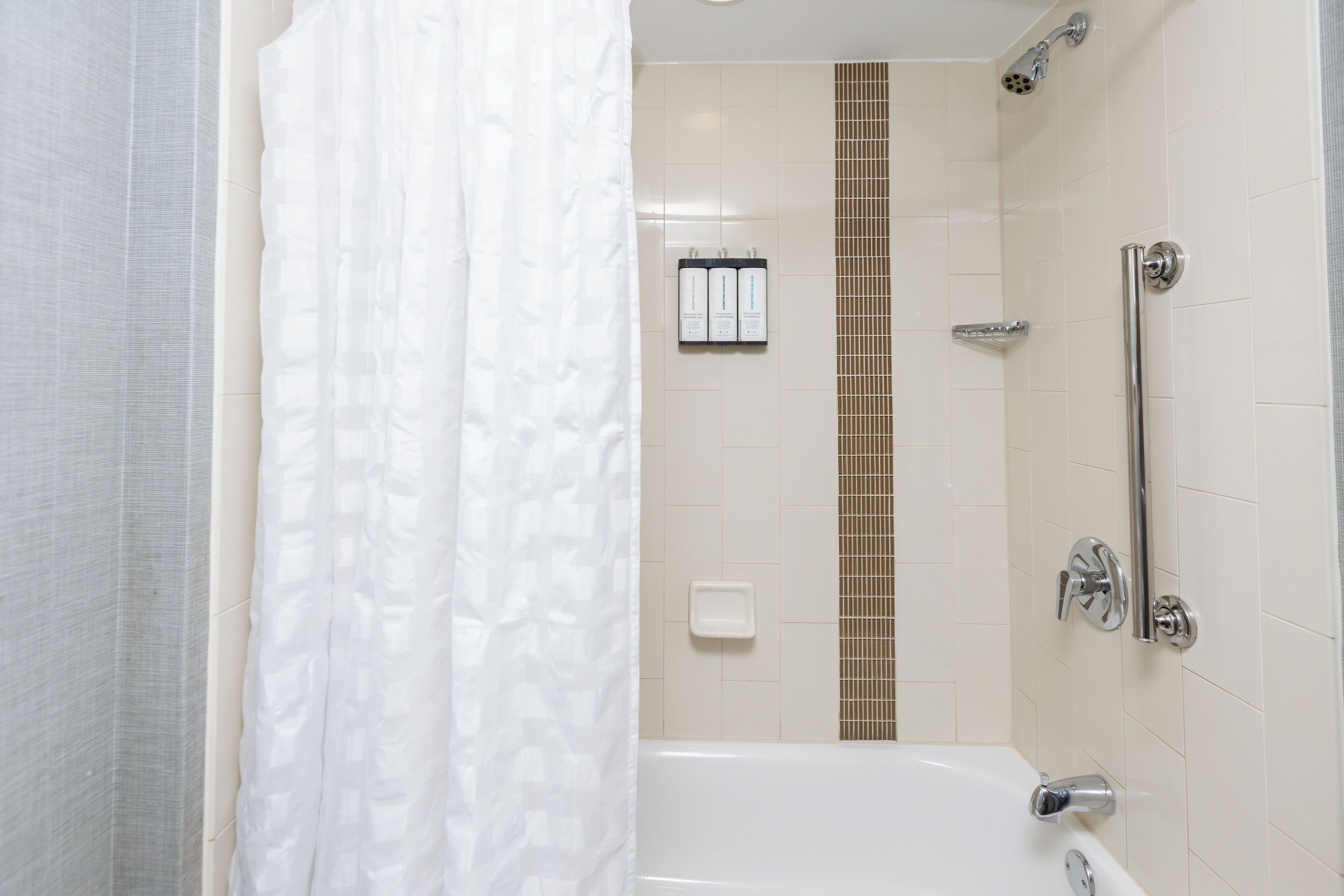 A bathroom with a bathtub, a shower, and a toilet. There are toiletries on the wall.