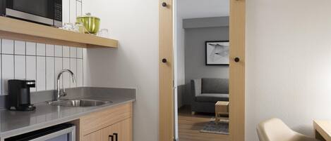 A modern kitchen with a built-in microwave, a coffee maker, and a refrigerator.