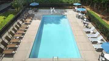 A rectangular pool with a clear blue water surface, surrounded by lounge chairs and umbrellas.