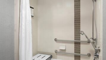 A shower area with a grab bar, a handheld showerhead, and a bathtub.