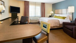 A hotel room with a bed, a desk, a chair, a television, and a window with curtains. - MainStay Suites Wichita Northeast (Wichita)
