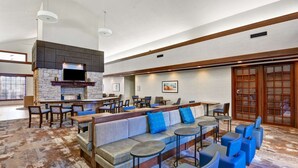 A spacious lobby with a long seating area, a fireplace, and a bar. - Homewood Suites Kansas City/Overland Park (Overland Park)
