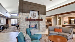 A spacious lobby with a stone fireplace, seating area, and a bar. - Homewood Suites Kansas City/Overland Park (Overland Park)