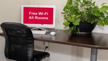 A desk with a computer, a chair, and a sign indicating free Wi-Fi availability.