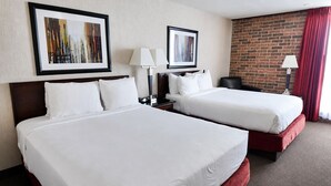 A hotel room with two beds, a brick wall, and two framed pictures on the wall. - Hotel Lotus Kansas City Merriam (Mission)