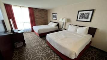 A hotel room with two beds, a desk, a chair, a lamp, and a picture on the wall.