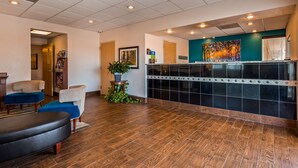 A reception area with a wooden floor, a reception desk, and a large painting on the wall.