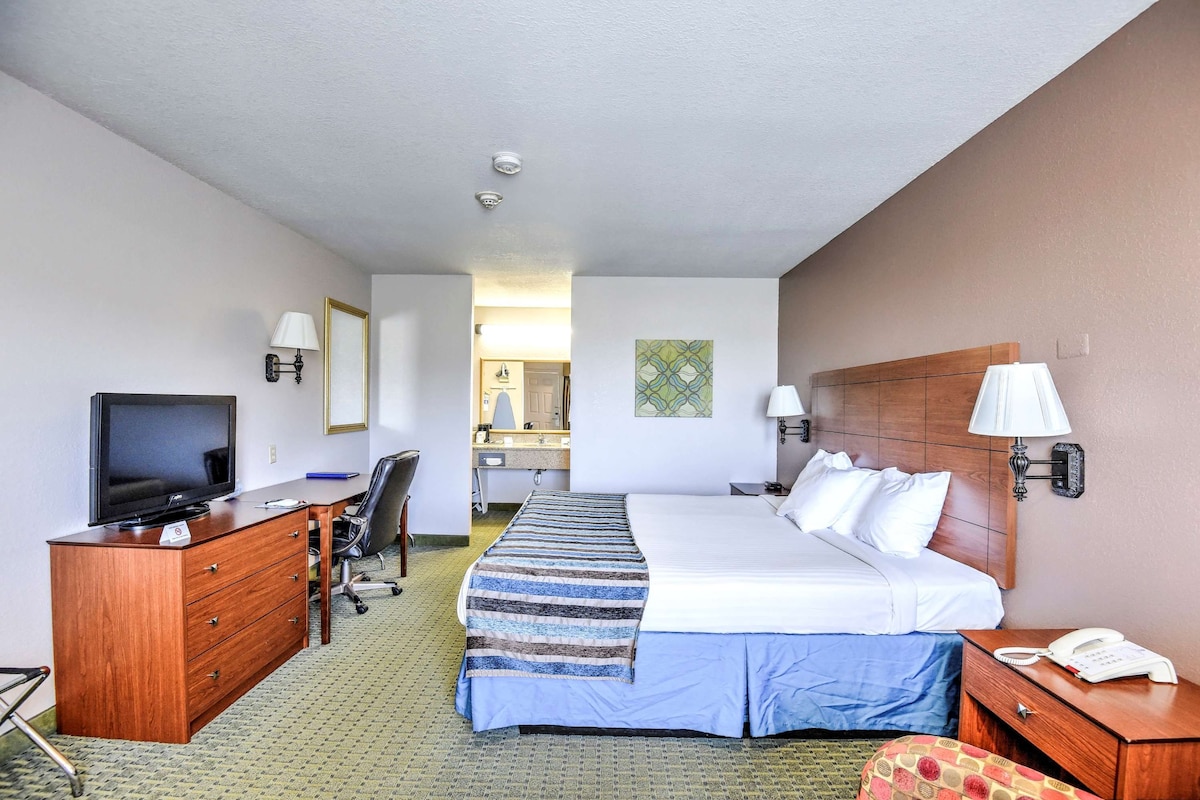A hotel room with a bed, a desk with a computer, a TV, a phone, and a mirror.