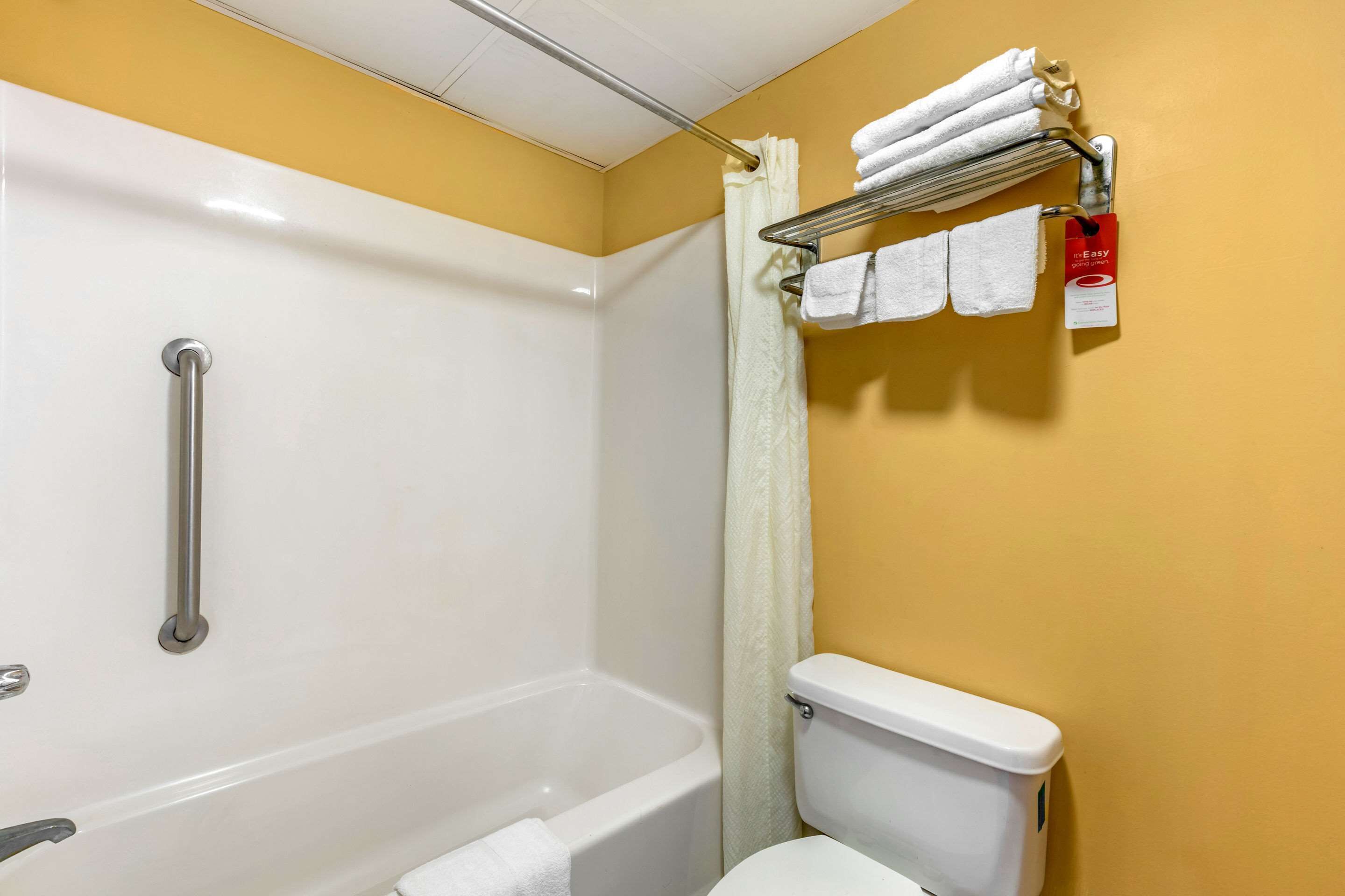 A bathroom with a bathtub, toilet, and a towel rack with towels.