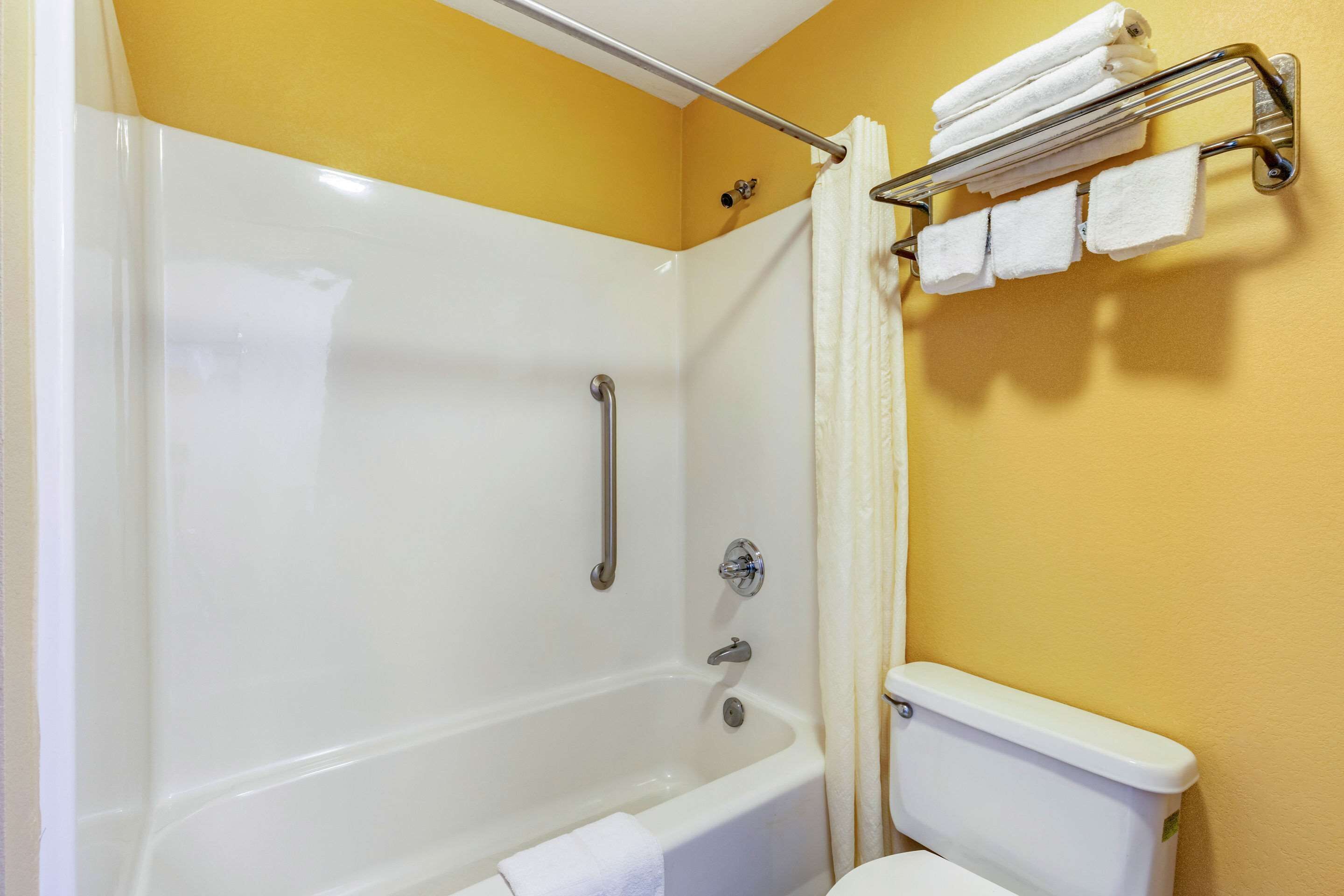 A bathroom with a bathtub, toilet, and towel rack.