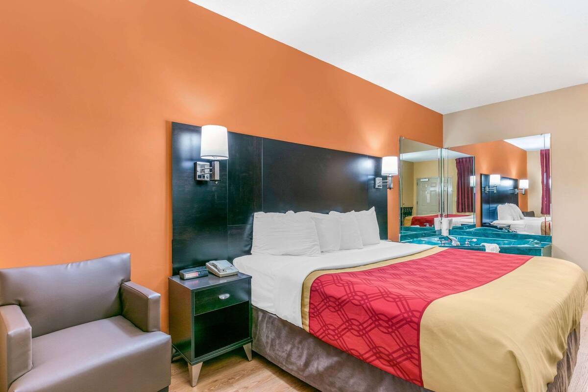 Ein Hotelzimmer mit einem großen Bett, einem Nachttisch, einem Stuhl und einem Spiegel.