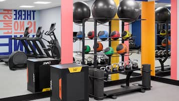 A gym with exercise equipment, including treadmills, a rack of medicine balls, and kettlebells.