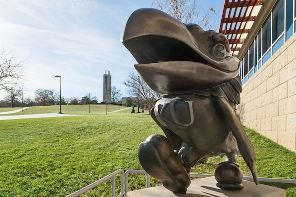 A sculpture of a horse's head in a public park with a building in the background.