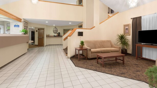 Eine geräumige Lobby mit einer Rezeption, einer Treppe, einem Sofa, einem Couchtisch und einem Fernseher.