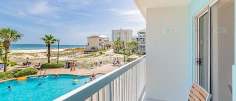 A balcony with a view of a swimming pool and beach.