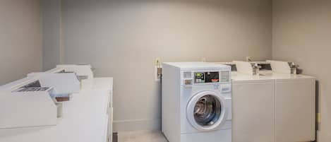 A laundry room with a front-loading washing machine and stacked dryers.