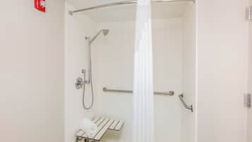 A shower with a handheld showerhead, a handheld showerhead, a towel rack, and a safety rail.