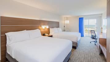 Habitación de hotel con dos camas, un escritorio, una silla, un teléfono y vista al océano.