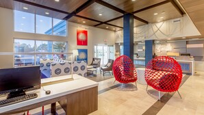 A modern reception area with a desk, computer, and red chairs. - Holiday Inn Express Orange Beach by IHG (Orange Beach)
