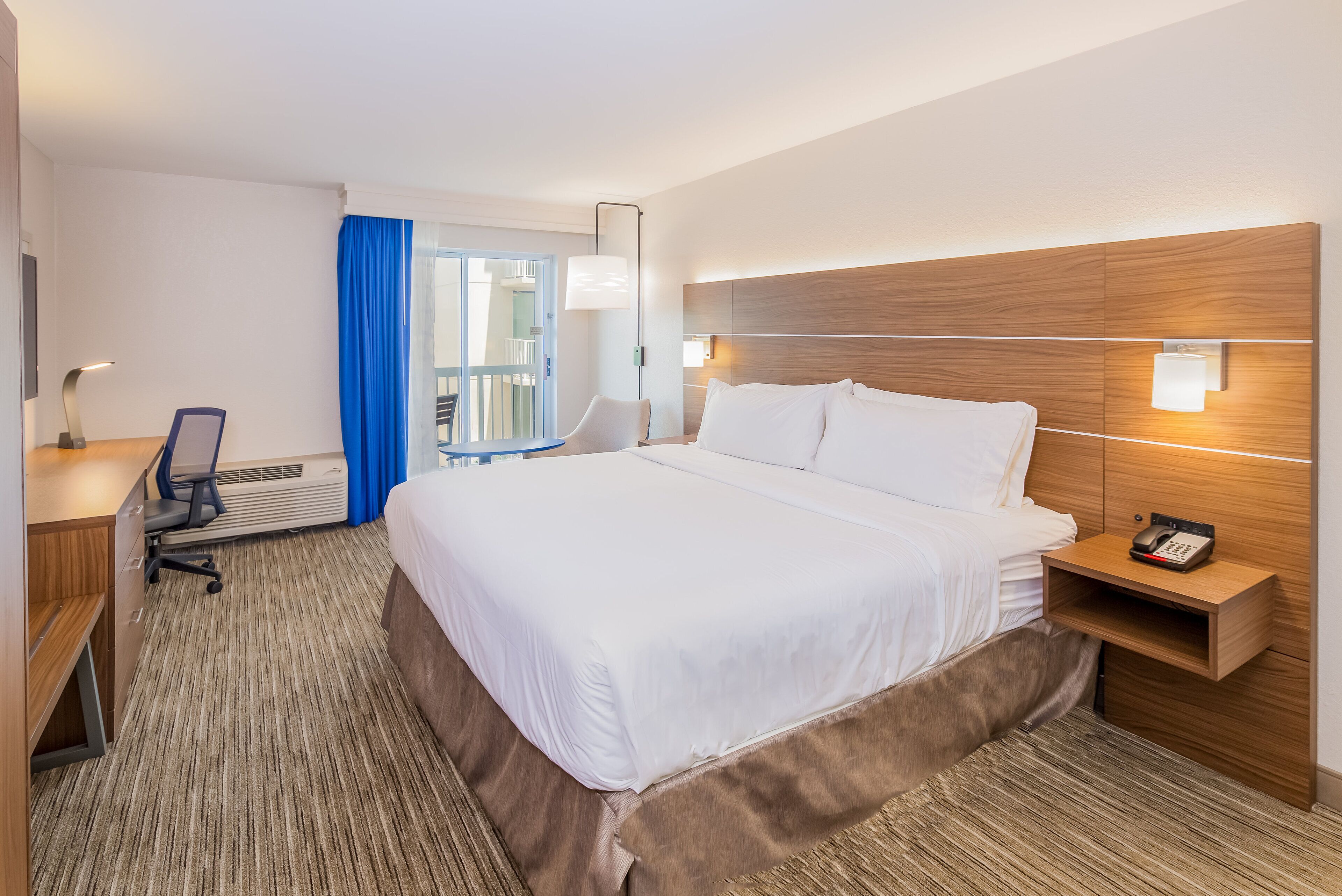 Une chambre d’hôtel avec un lit, un bureau, une chaise et une vue sur le balcon.