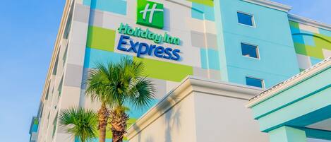 A Holiday Inn Express building with a modern design, featuring a prominent logo and a clear sky in the background.