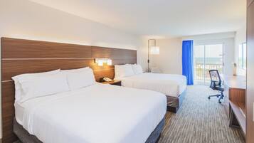 Une chambre d’hôtel avec deux lits, un bureau, une chaise et une vue sur l’océan.
