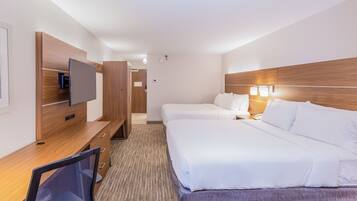 Habitación de hotel con escritorio de madera, televisor de pantalla plana, dos camas y piso alfombrado.