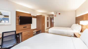 A hotel room with a bed, a desk, a chair, a TV, and a door.