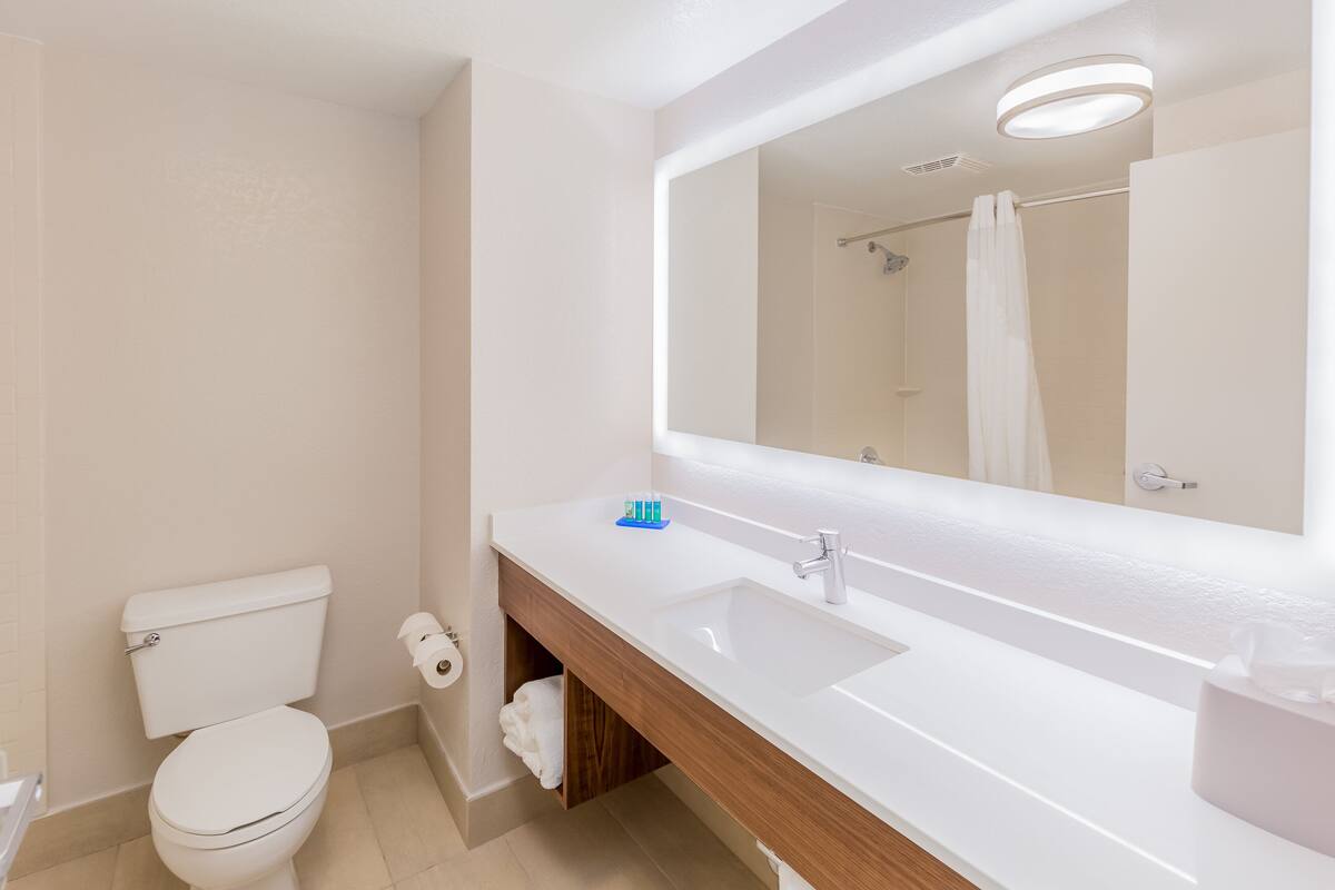 Un baño moderno con inodoro, lavamanos y espejo.