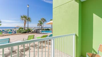 A balcony with a view of a pool area, including lounge chairs and umbrellas.