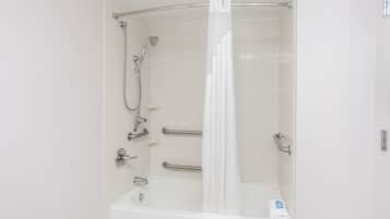 Un baño blanco con bañera, ducha y barras de apoyo.