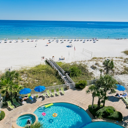 A beach resort with a swimming pool, lounge chairs, and umbrellas.